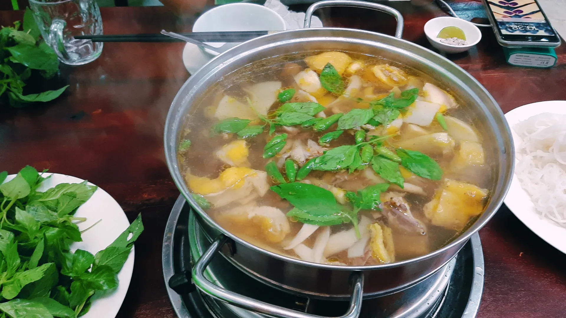 Ảnh nồi lẩu gà lá é đang sôi sùng sục, bên cạnh là hai thanh cơm lam nướng